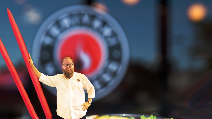 The CEO of Teriyaki Madness, Michael Haith stands next to a blow up picture of a Teriyaki Bowl.